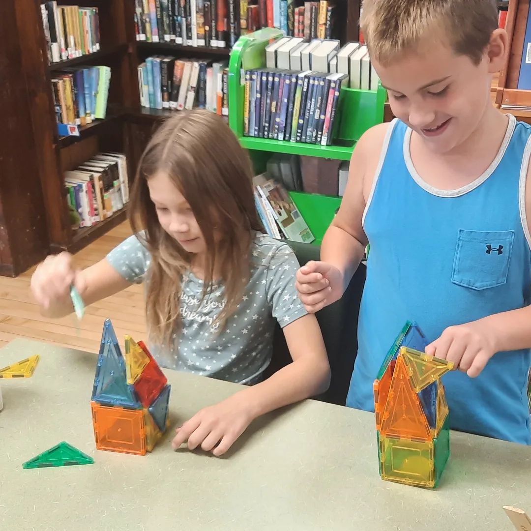 Two children building towers out of magnetic tiles.