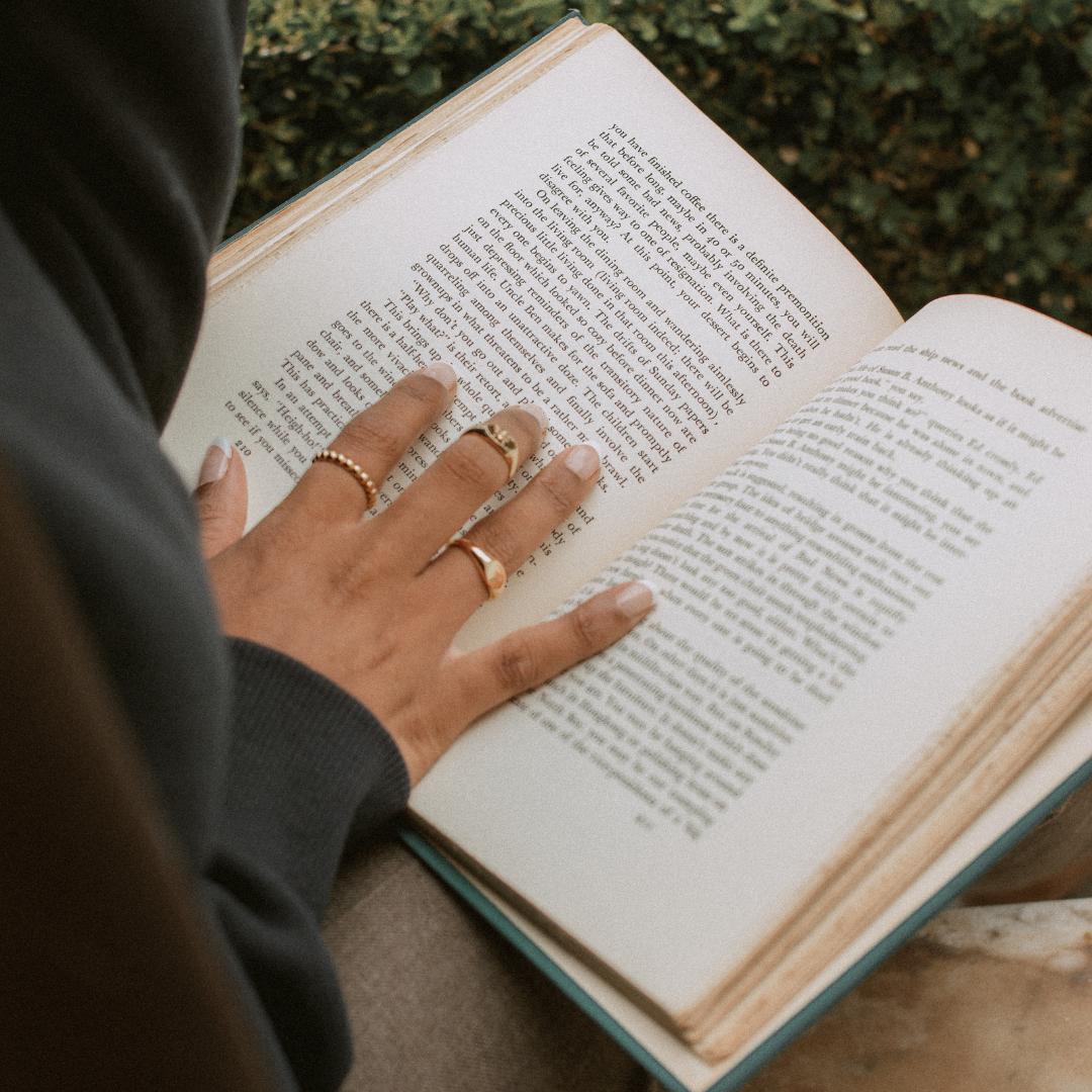 person reading book, hand on page, decorative